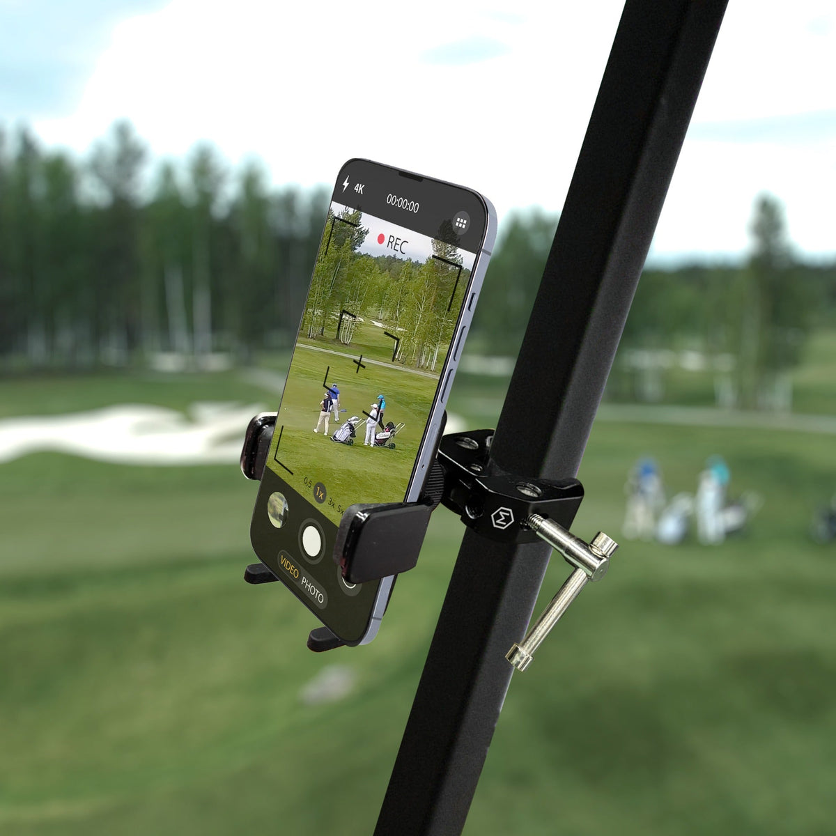 Close-up of black adjustable phone holder attached to a golf cart, holding a smartphone for recording or navigation during outdoor activities.